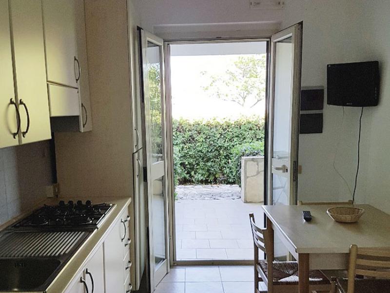 Cucina luminosa, porta aperta su giardino verde, atmosfera semplice e accogliente.