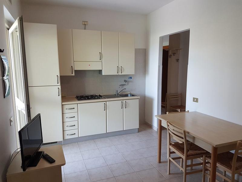 Cucina luminosa e accogliente, con mobili chiari e tavolo semplice, atmosfera serena.