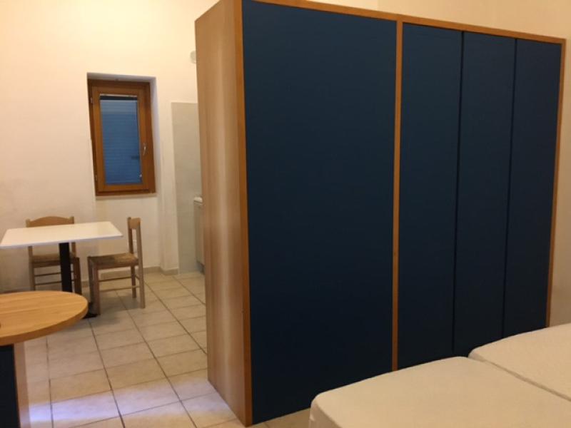 Cucina moderna e luminosa, minimalista, con mobili chiari e un piccolo televisore.