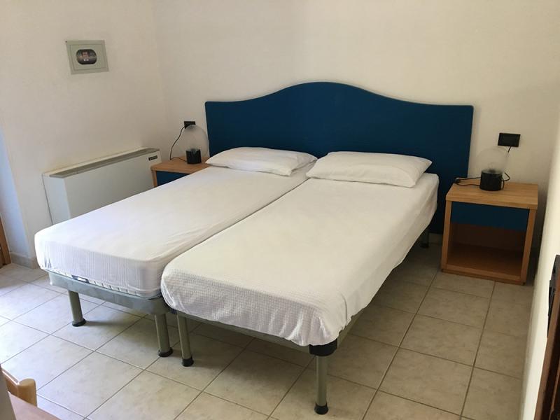 Sala luminosa e accogliente con divano verde, tavolo in legno e porta aperta.