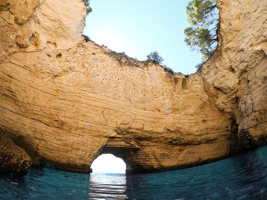 Cielo azzurro incorniciato da scogliere dorate, acqua limpida, natura selvaggia e pace assoluta.